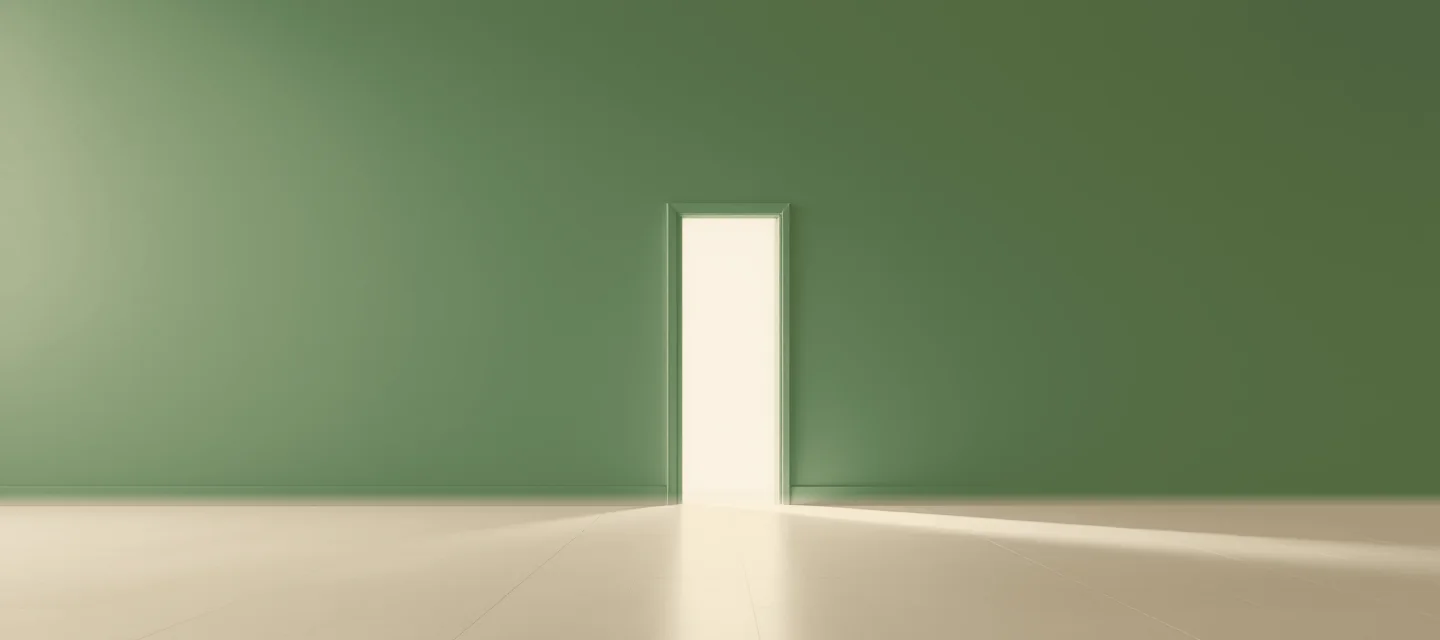 Le voyage du héros : 8 étapes pour comprendre vos transitions Une porte entrouverte dans un mur vert sauge, d'où entre une lumière chaude qui s'étend sur le sol